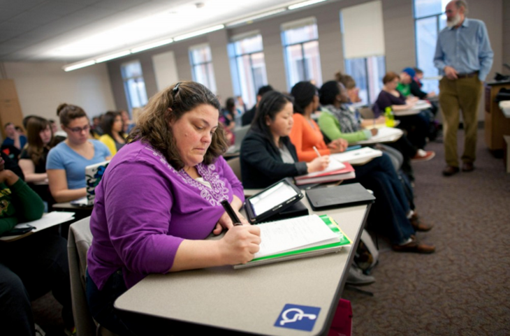 Students Writing At Desks In Classroom